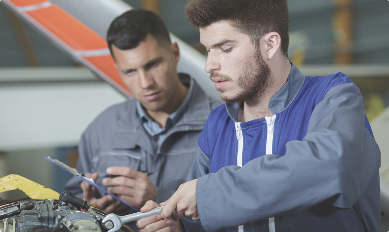 Two aviation technicians working on an aircraft engine