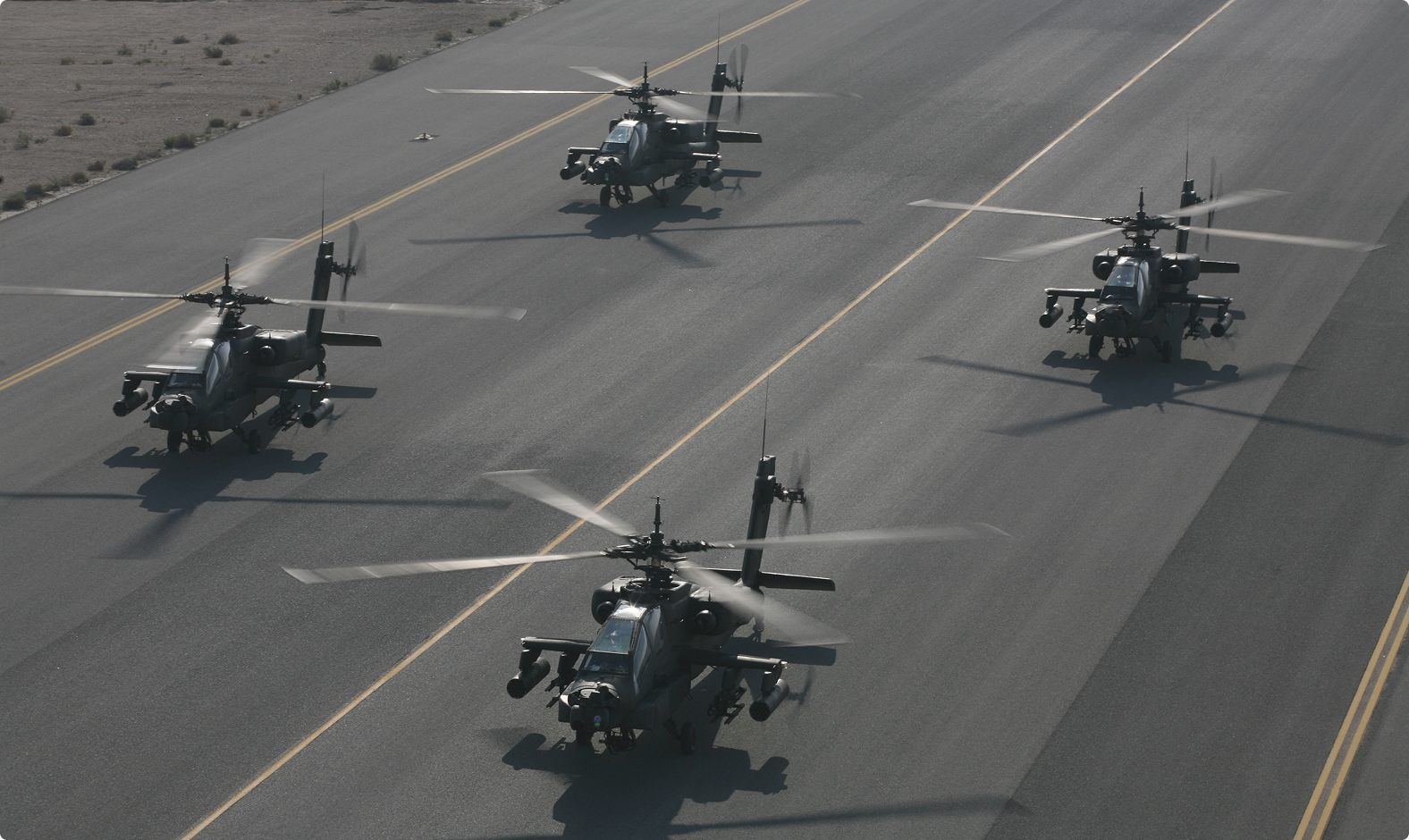 Four military helicopters on a runway